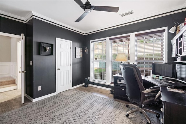 office with a ceiling fan, a decorative wall, visible vents, and crown molding