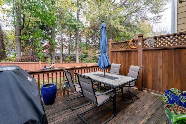 deck with outdoor dining space, a grill, and fence