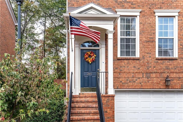 view of exterior entry featuring brick siding and an attached garage