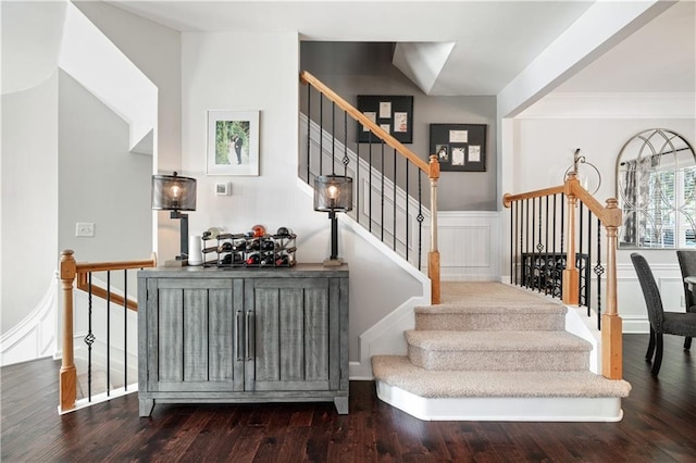 stairway featuring ornamental molding, wainscoting, wood finished floors, and a decorative wall