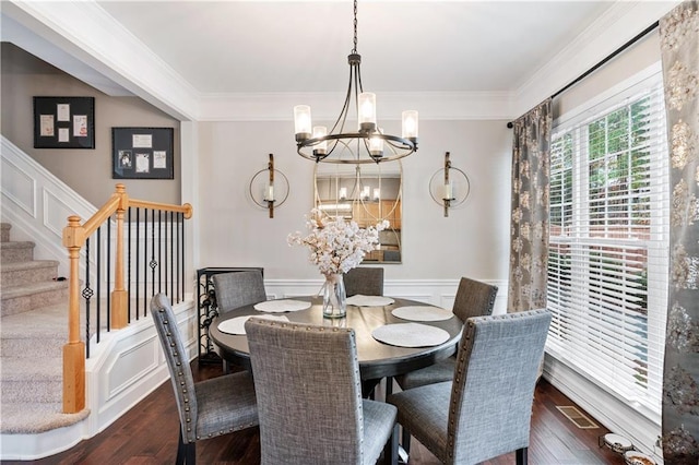 dining space featuring wainscoting, stairway, wood finished floors, crown molding, and a chandelier