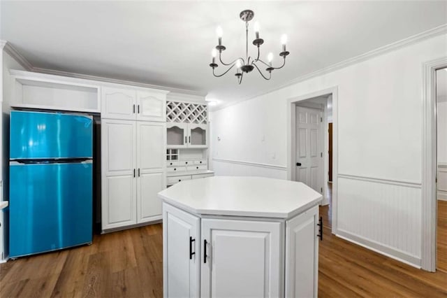 kitchen with freestanding refrigerator, ornamental molding, dark wood-type flooring, white cabinetry, and a chandelier