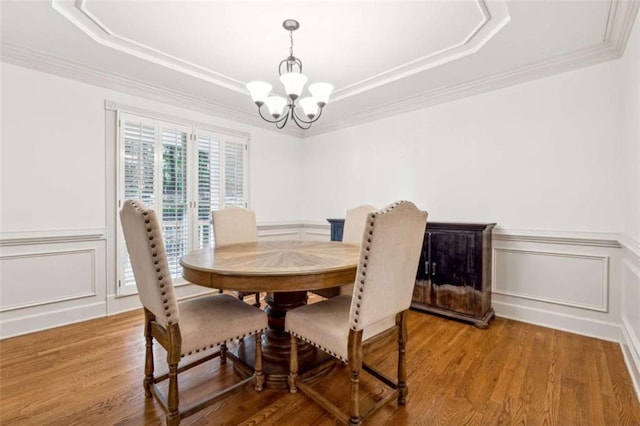 dining room with a tray ceiling, wood finished floors, and a chandelier