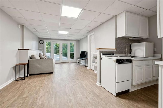 kitchen featuring tasteful backsplash, open floor plan, light wood-type flooring, french doors, and white range