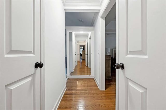 hallway featuring crown molding, baseboards, and wood finished floors