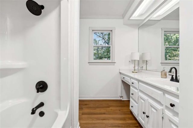 full bathroom with vanity, wood finished floors, baseboards, ornamental molding, and shower / bathtub combination