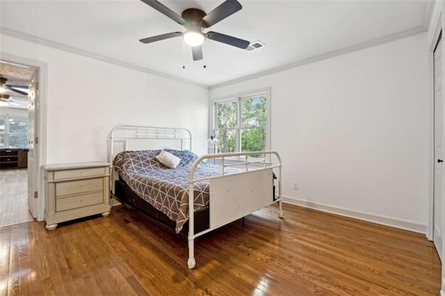 bedroom featuring visible vents, wood-type flooring, multiple windows, and crown molding