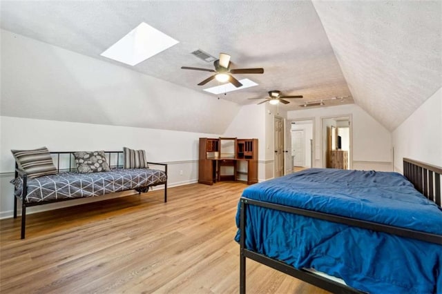 bedroom with lofted ceiling with skylight, visible vents, a textured ceiling, and wood finished floors