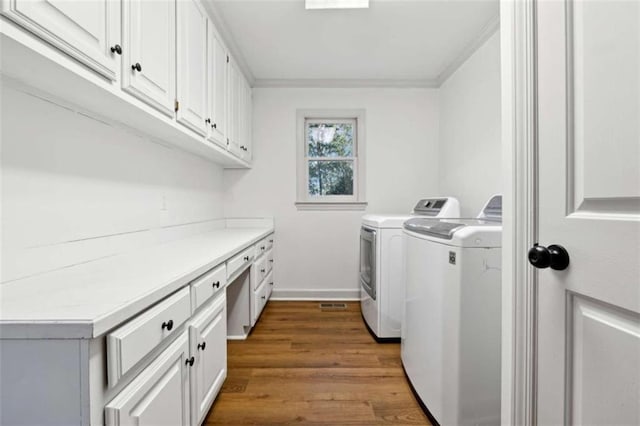 washroom with wood finished floors, baseboards, cabinet space, crown molding, and independent washer and dryer