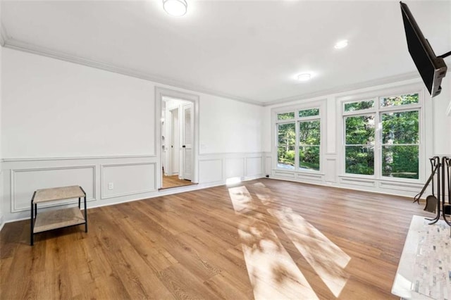 living room featuring a decorative wall, crown molding, and wood finished floors