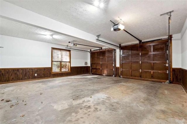 garage with a wainscoted wall, wooden walls, and a garage door opener