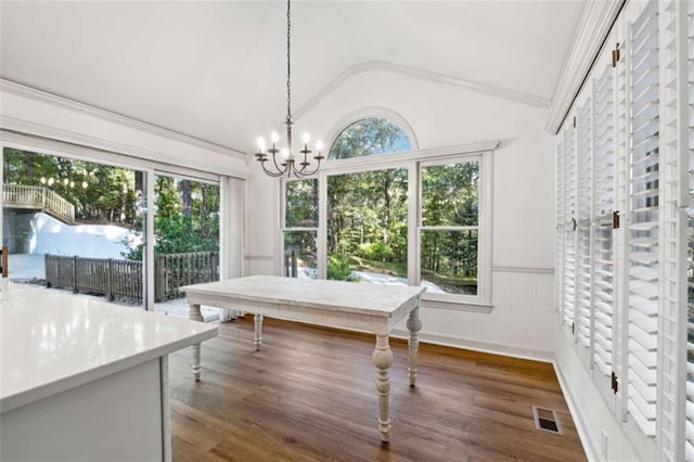 dining room with a wainscoted wall, a healthy amount of sunlight, wood finished floors, and vaulted ceiling