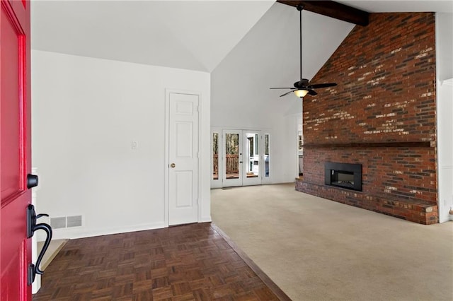 unfurnished living room featuring beamed ceiling, ceiling fan, french doors, a brick fireplace, and high vaulted ceiling