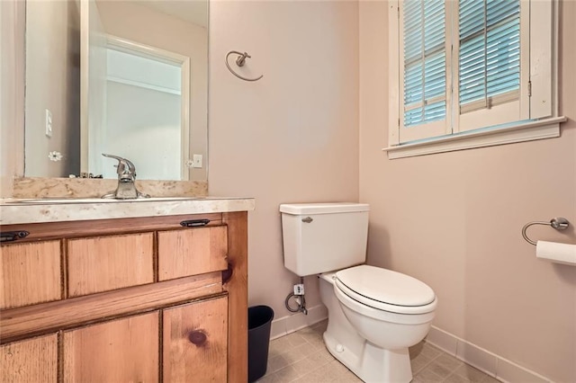 bathroom with toilet, tile patterned floors, baseboards, and vanity