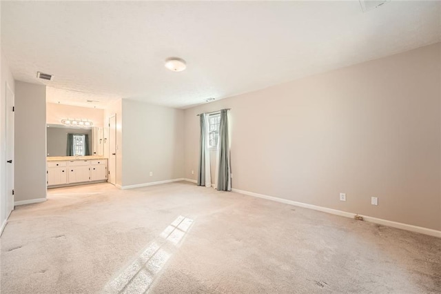 unfurnished bedroom featuring light carpet, connected bathroom, visible vents, and baseboards