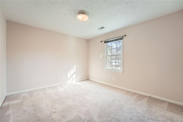 carpeted empty room featuring a textured ceiling, visible vents, and baseboards