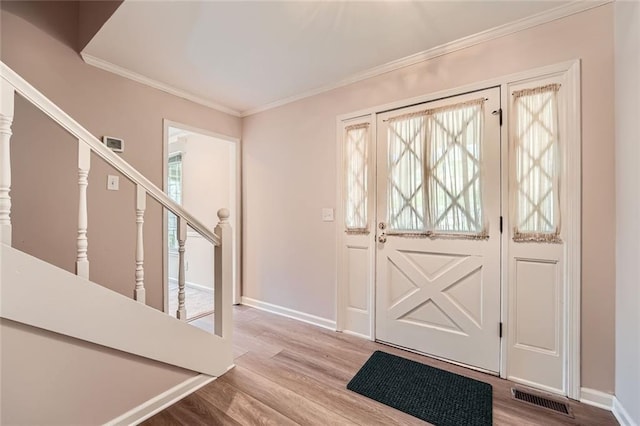 foyer featuring visible vents, crown molding, baseboards, and wood finished floors