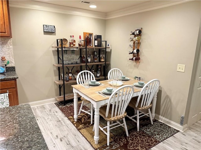 dining area featuring baseboards, visible vents, light wood-style flooring, and ornamental molding