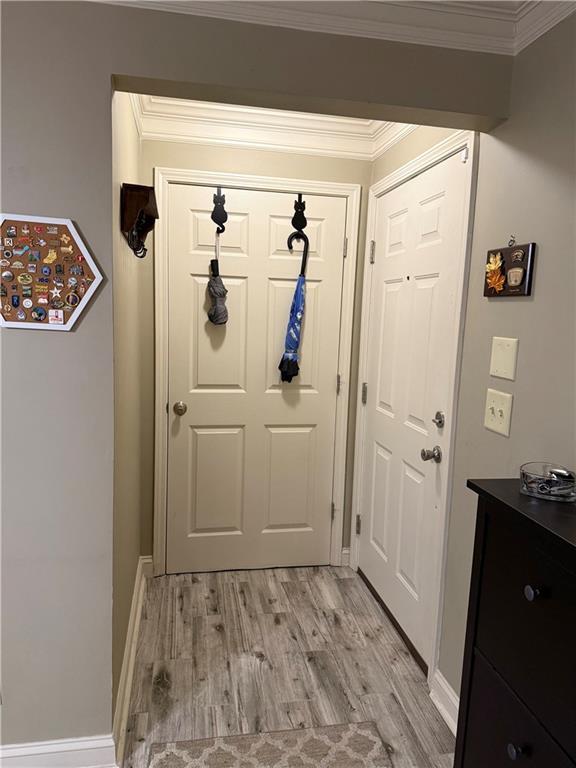 doorway with baseboards, light wood-style floors, and ornamental molding