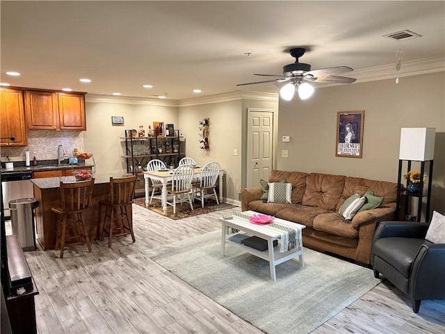 living area with ceiling fan, recessed lighting, ornamental molding, and light wood finished floors