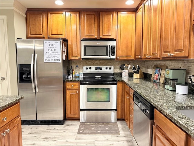 kitchen featuring light wood-type flooring, appliances with stainless steel finishes, brown cabinetry, and decorative backsplash