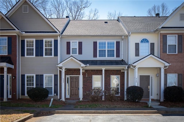 multi unit property featuring a shingled roof and brick siding