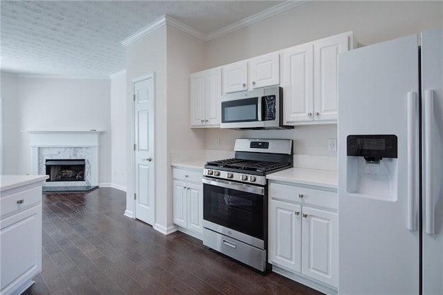 kitchen with white cabinets, ornamental molding, dark wood-type flooring, stainless steel appliances, and light countertops