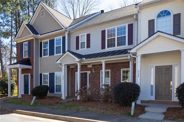 multi unit property featuring a standing seam roof, roof with shingles, metal roof, and brick siding