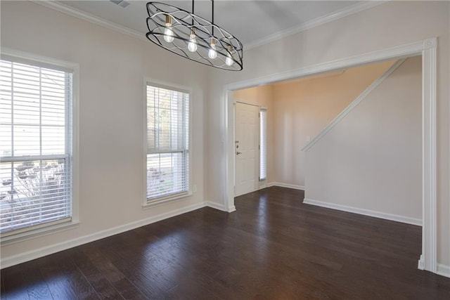 foyer with a wealth of natural light, ornamental molding, a notable chandelier, and wood finished floors