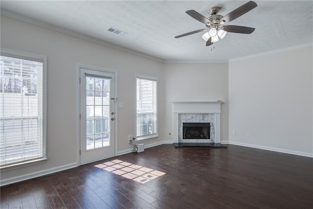 unfurnished living room with visible vents, wood-type flooring, a premium fireplace, ornamental molding, and a textured ceiling