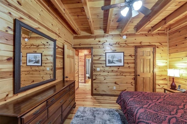 bedroom with wood walls, beamed ceiling, wooden ceiling, and light hardwood / wood-style floors