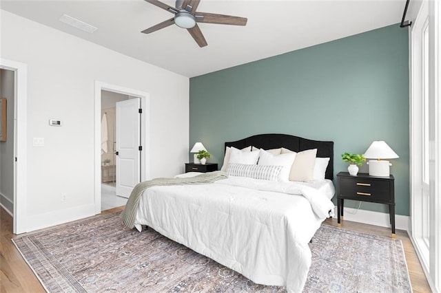 bedroom with ceiling fan, connected bathroom, and light hardwood / wood-style floors