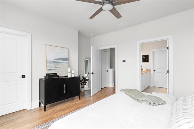 bedroom with ceiling fan, ensuite bath, and light hardwood / wood-style floors