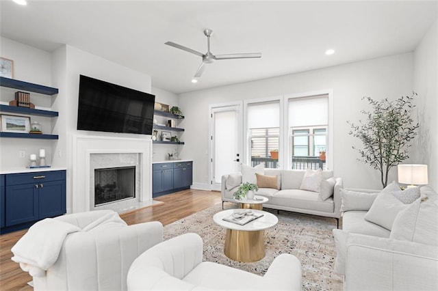 living room with ceiling fan, a fireplace, and light hardwood / wood-style floors