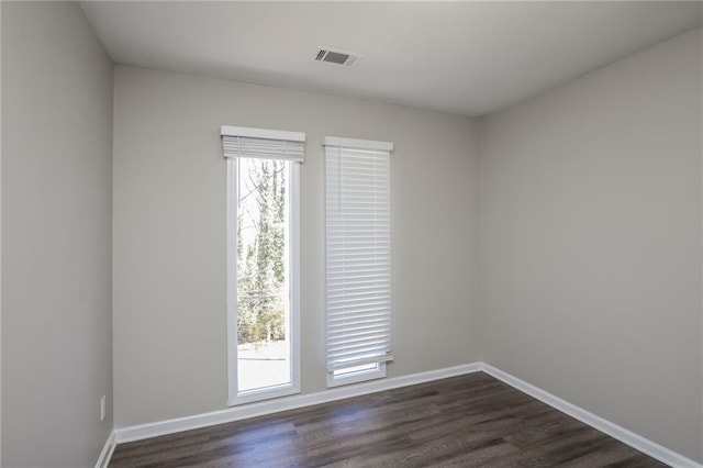 spare room with baseboards, visible vents, and dark wood-type flooring