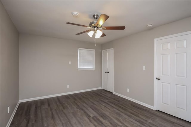 spare room featuring dark wood-style flooring, ceiling fan, and baseboards