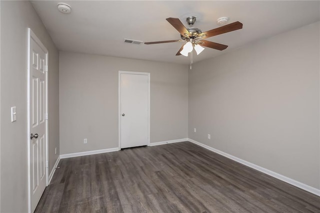 unfurnished room featuring ceiling fan, baseboards, visible vents, and dark wood finished floors