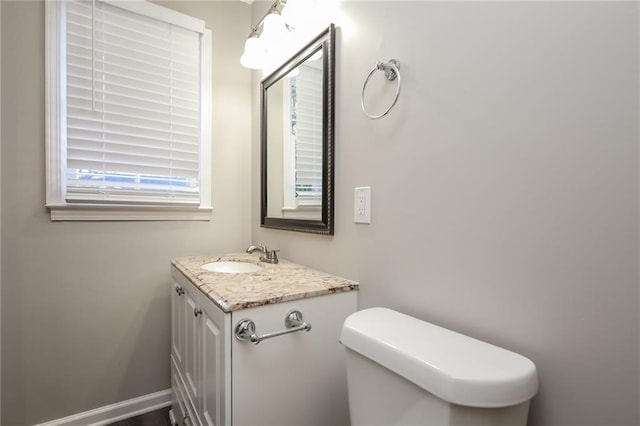 bathroom featuring toilet, baseboards, and vanity