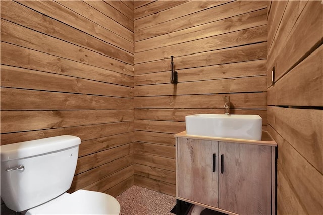 bathroom with vanity, wooden walls, and toilet