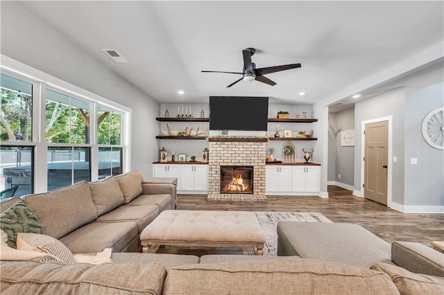 living room with hardwood / wood-style flooring, a brick fireplace, and ceiling fan