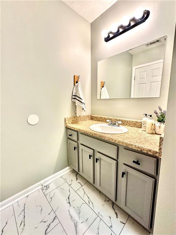 bathroom featuring vanity, marble finish floor, baseboards, and visible vents