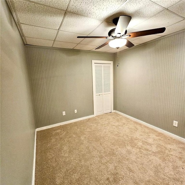 carpeted empty room featuring baseboards, a ceiling fan, and a paneled ceiling
