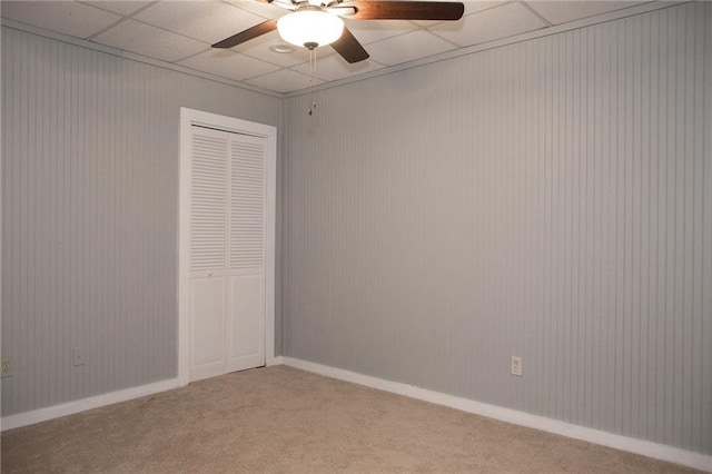 empty room featuring a ceiling fan, a paneled ceiling, and light colored carpet