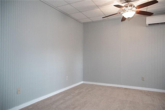 carpeted spare room featuring a paneled ceiling, a ceiling fan, and a wall unit AC