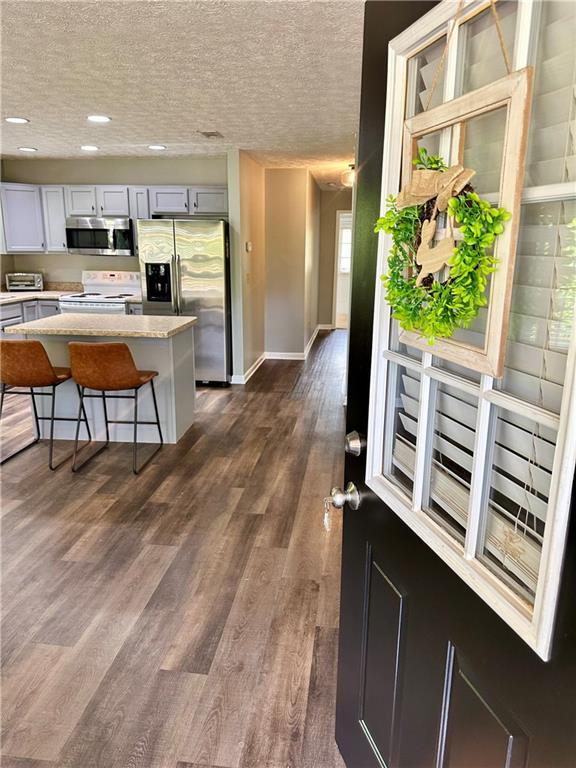 kitchen featuring dark wood-style floors, a textured ceiling, recessed lighting, light countertops, and appliances with stainless steel finishes
