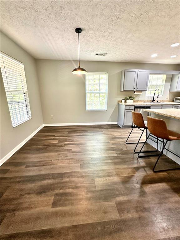 kitchen with baseboards, a textured ceiling, visible vents, and plenty of natural light