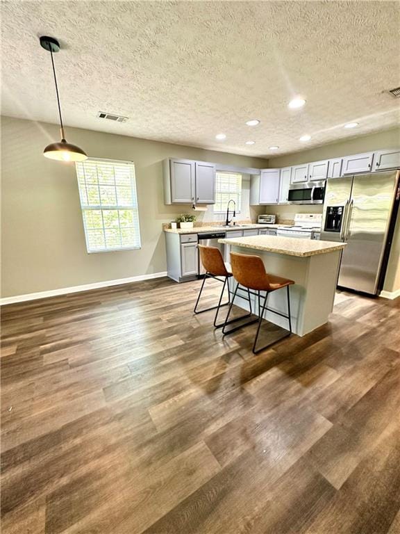 kitchen featuring dark wood-style floors, appliances with stainless steel finishes, a textured ceiling, and visible vents
