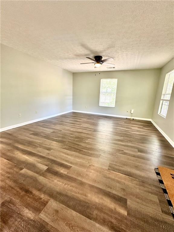 empty room with plenty of natural light, a textured ceiling, and ceiling fan