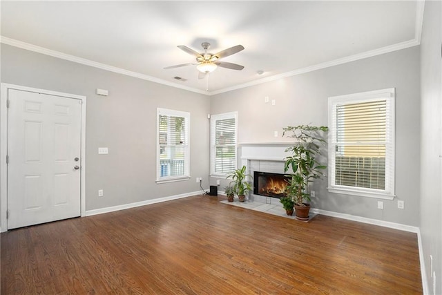 unfurnished living room with ceiling fan, dark hardwood / wood-style floors, a tiled fireplace, and ornamental molding