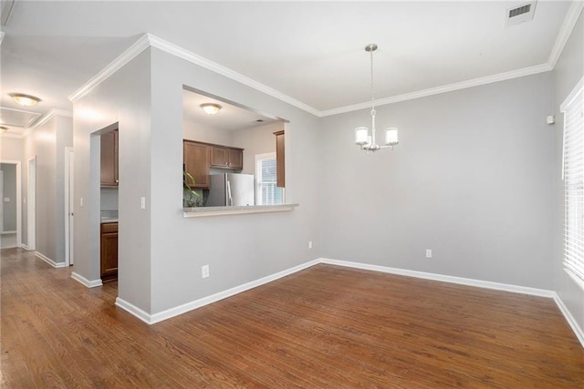 spare room featuring an inviting chandelier, dark hardwood / wood-style floors, and crown molding